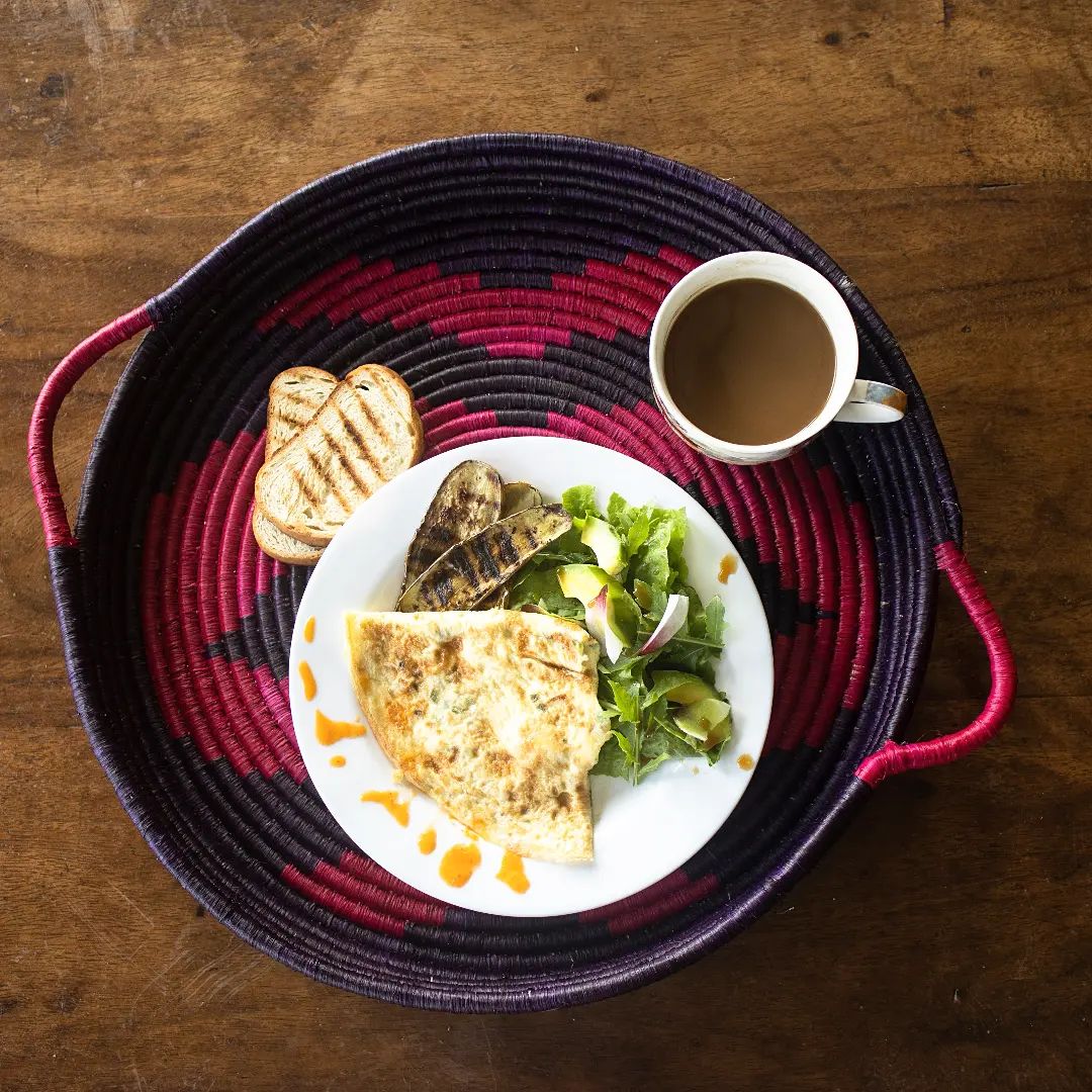 Breakfast is served 🍳any time, any place.Spanish omelette, crispy roasted eggplant, coffee just the way you like it and green salad with turmeric flowers all from the garden 🌿Side note: one of the fishing cooperative members on the island made this super strong and pretty tray and we love it!#oneminutesouth #islandlife #vegeterian #foodies #breakfast #brunch #chef #villaholiday #holiday #vacation #bulagoisland #uganda #papyrustray #lakevictoria #equator #islandholiday